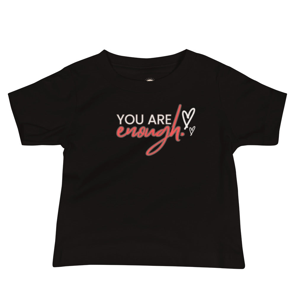 Black baby t-shirt with cream text “You Are,” bold red “Enough,” and two cream hearts, symbolizing confidence and self-worth.