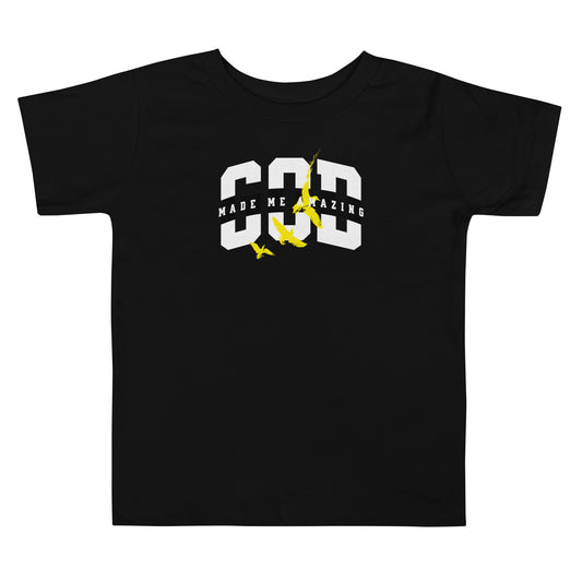 Toddler t-shirt with bold white lettering “God Made Me Amazing” and yellow bird design, promoting confidence, faith, and joy.